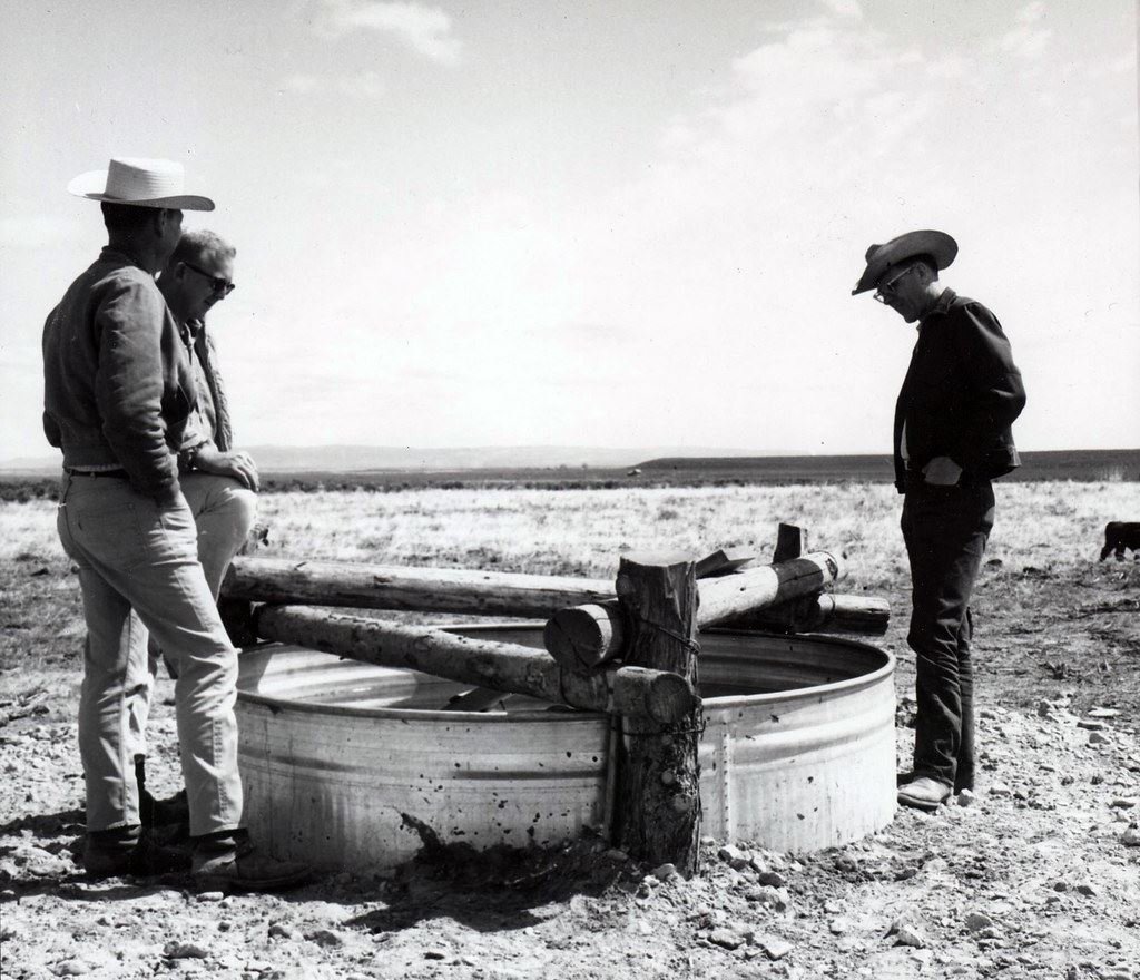 Rancheros con sombrero platicando junto a un abrevadero